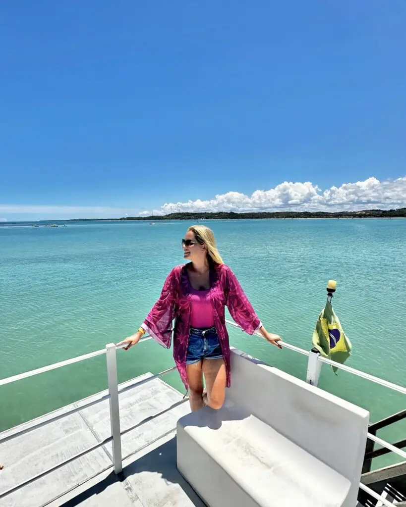 Cris no barrco, com mar ao fundo. Passeio de barco para conhecer as piscinas naturais da região.